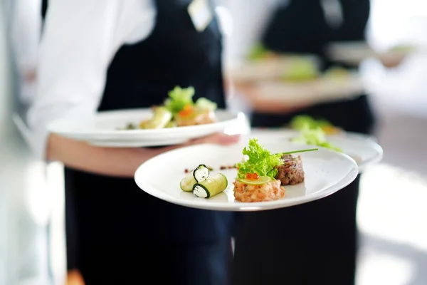 Waiters carrying plates with meat