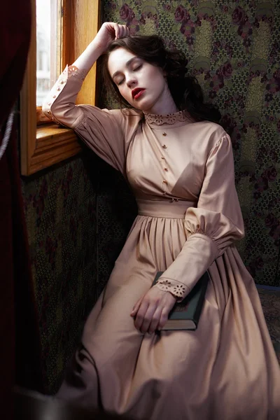 Young woman in beige vintage dress of early 20th century sleapin