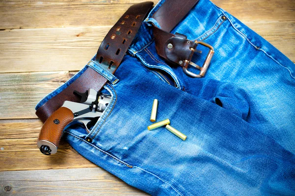 Old blue jeans with silver revolver in his pocket