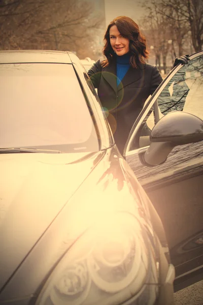 Smiling woman in a dark coat opened the car door