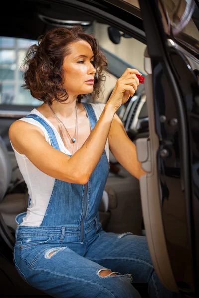 Mechanic woman in a blue overalls repair with a screwdriver the
