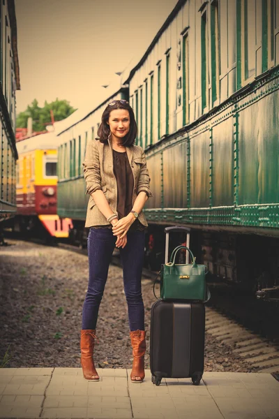 Pretty adult woman with a luggage near the train