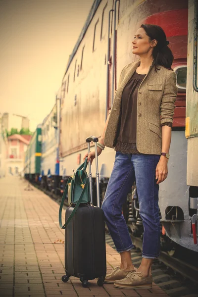 Beautiful middle-aged woman with luggage rides in retro trip