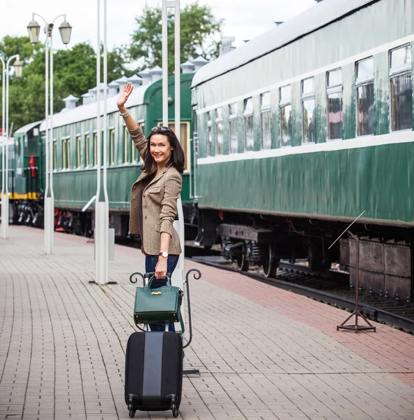 Smiling beautiful middle-aged woman with a suitcase and handbag