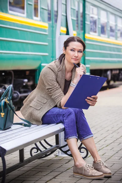 Beautiful middle-aged woman-traveler sitting on a bench, holding