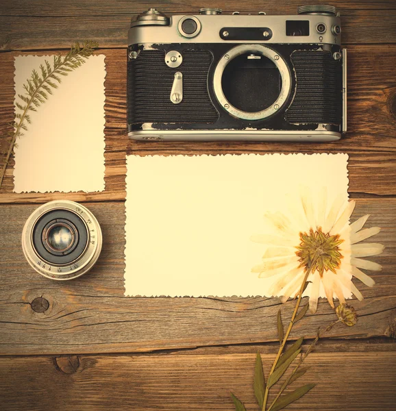 Mockup stillife with retro photo, camera, lens and pressed plant