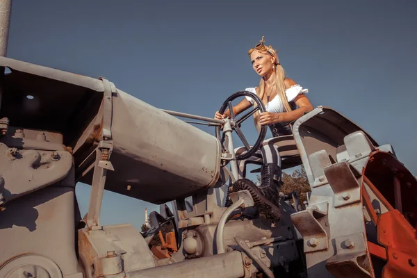 Sexy woman in the steam-punk clothes is driving vintage tractor.