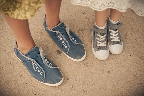 Mother and daughter in summer shoes on the beach