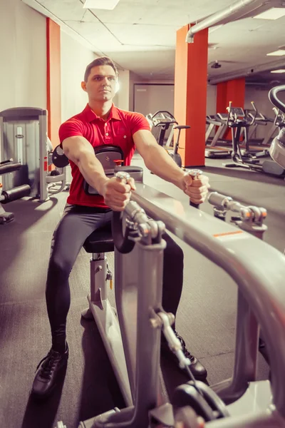 Young powerful man is doing exercises in the sport club.