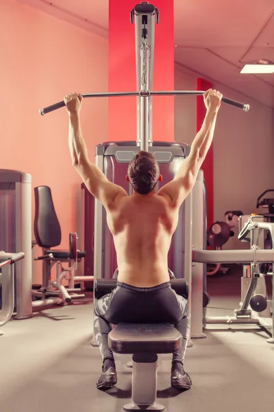 Young powerful man is doing exercises in the sport club.