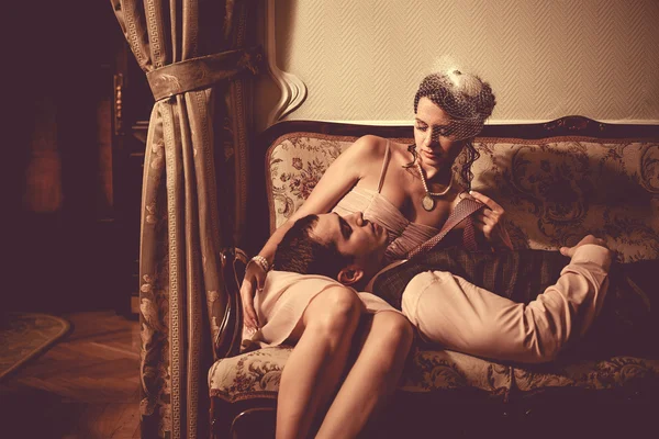 Young flirting couple is laying on the sofa. Vintage post proces