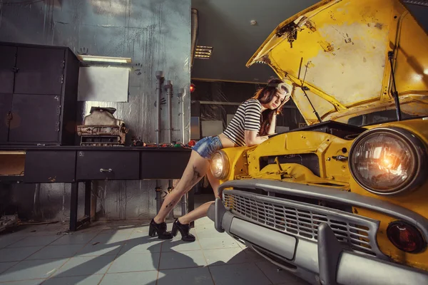 Woman mechanic in sexy shirts is thinking how to repair an old c