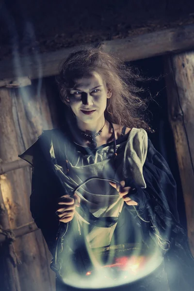 Pretty sorceress with the magic cauldron