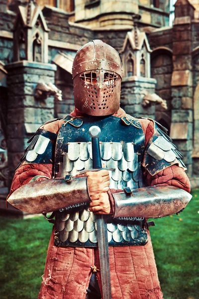 Medieval knight with the sword on the ancient castle background