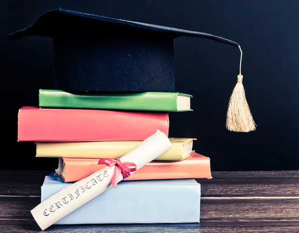 A mortarboard and graduation scroll on books