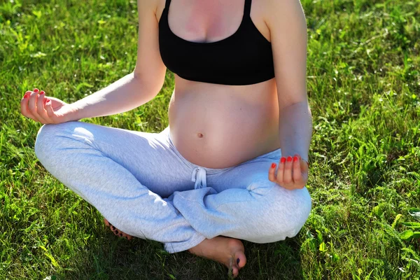 Pregnant woman doing yoga outdoors
