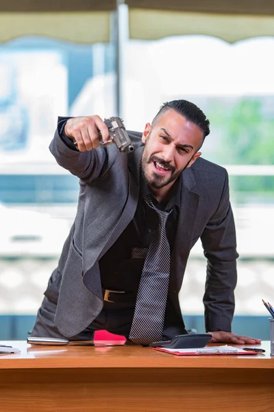 Angry aggressive businessman with gun in the office