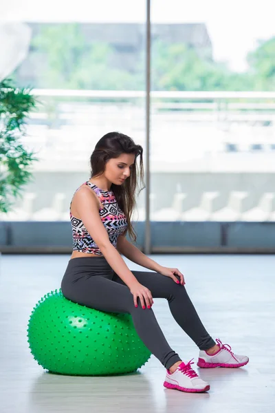 Young woman exercising with swiss ball in health concept