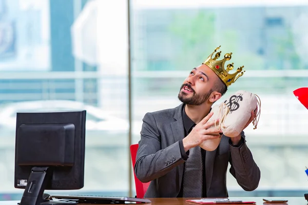 Businessman with crown and money sacks in the office