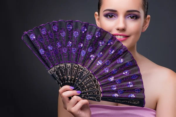 Nice woman with fan against gray background