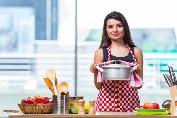 Female cook preparing soup in brightly lit kitchen