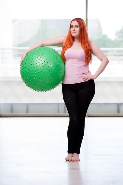 Young woman exercising with swiss ball in health concept