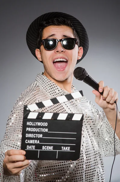 Young cheerful man with clapperboard and microphone