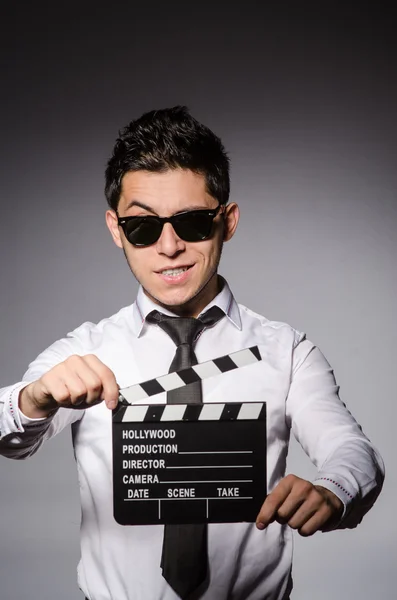 Young caucasian man with clapperboard against gray