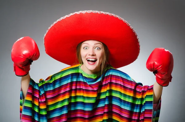 Girl in mexican vivid poncho and box gloves against gray