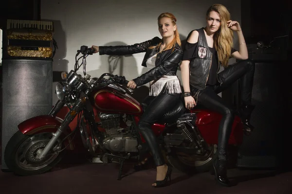 Two beautiful rock girl friends at rock club with motorcycle