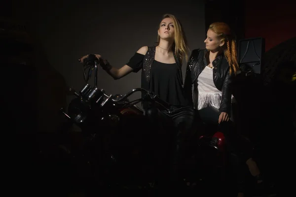 Two beautiful rock girl friends at rock club with motorcycle