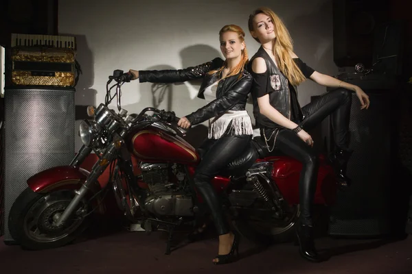 Two beautiful rock girl friends at rock club with motorcycle