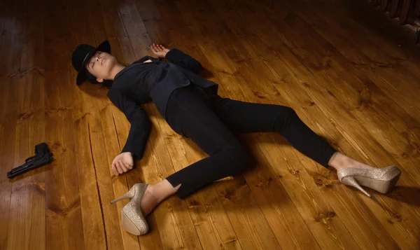 Woman in a black suit with gun lying on the floor