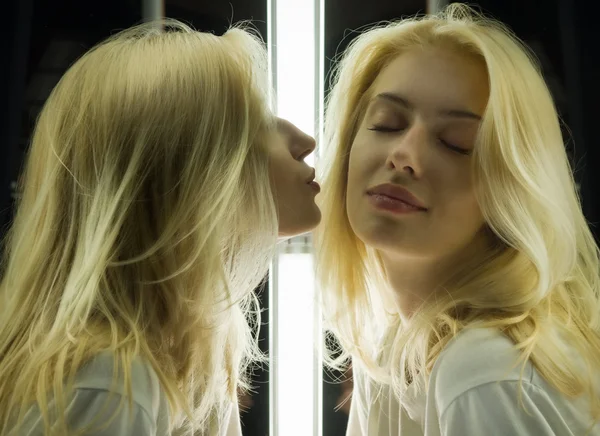 Mirrored shot of a gorgeous blond kissing herself