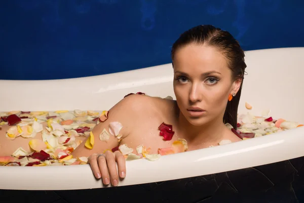 Beautiful sexy woman in bath with flowers petals