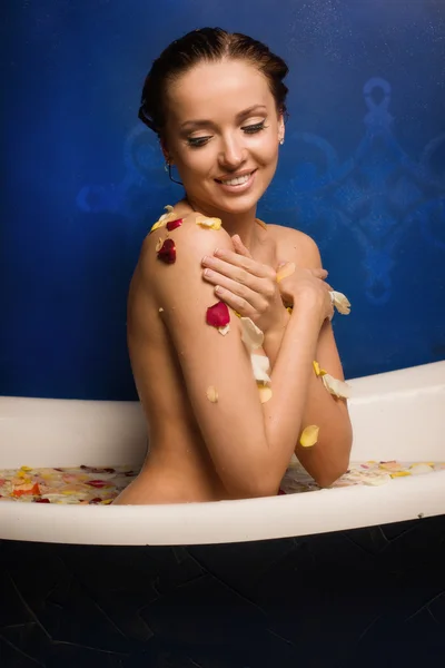 Beautiful sexy woman in bath with flowers petals