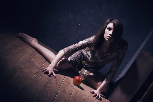Lonely mad woman with red apple sitting on a floor