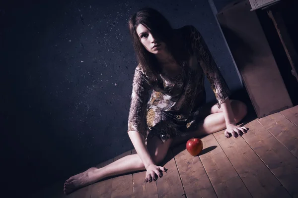 Lonely mad woman with red apple sitting on a floor