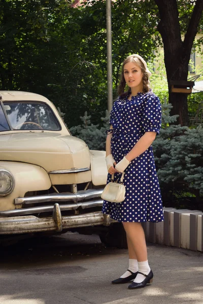 Lady in vintage dress standing near retro car