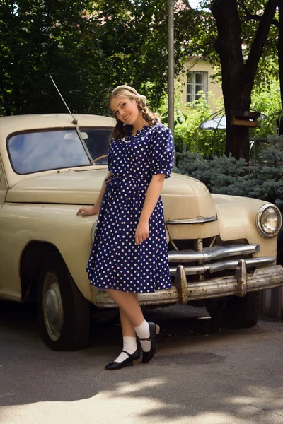 Lady in vintage dress standing near retro car