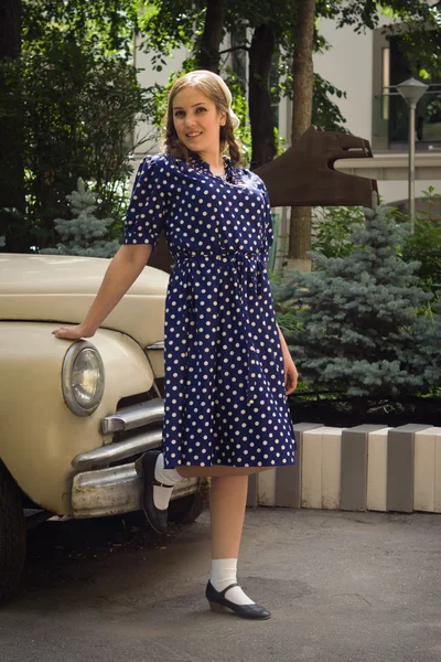 Lady in vintage dress standing near retro car