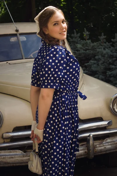 Lady in vintage dress standing near retro car