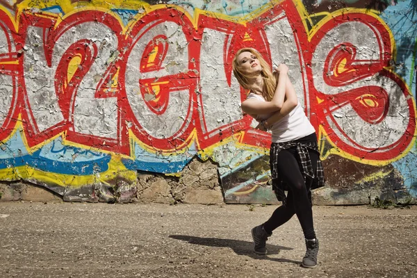 Young girl dancing on graffiti background