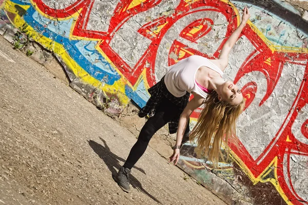 Young girl dancing on graffiti background