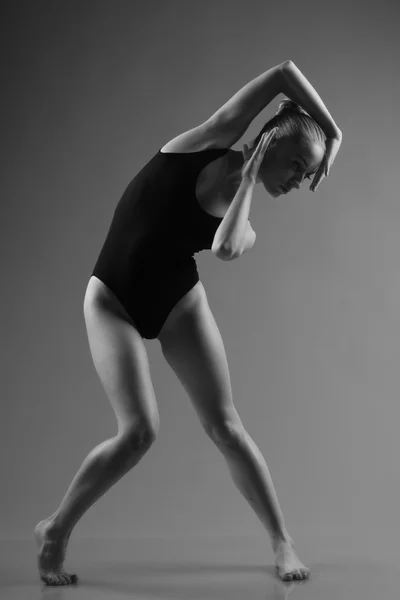 Modern ballet dancer posing on dark background