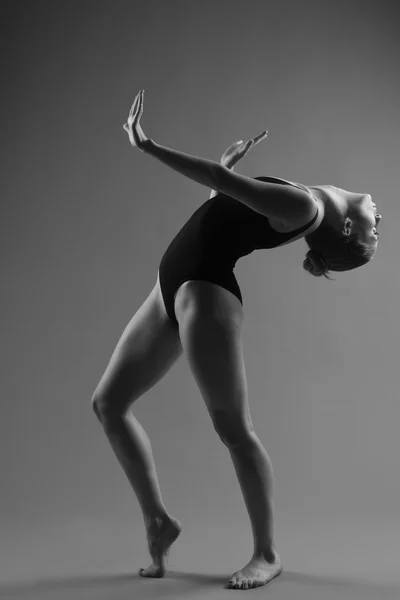 Modern ballet dancer posing on dark background