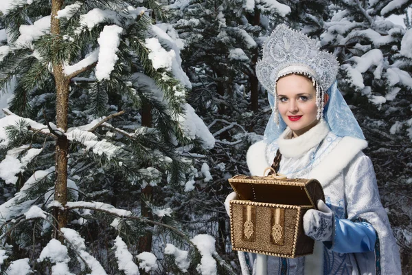 Snegurochka (Snow Maiden) with gifts bag in the winter forest
