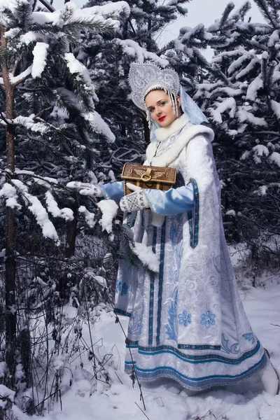 Snegurochka (Snow Maiden) with gifts bag in the winter forest