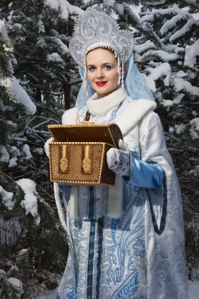 Snegurochka (Snow Maiden) with gifts bag in the winter forest