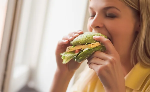 Woman eating vegan burger in restaurant